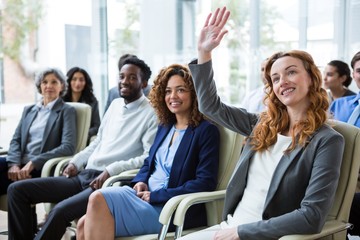 Businesswoman raising hand during meeting - Powered by Adobe