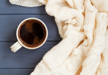 Fototapeta na wymiar Cup of black coffee, white knitted plaid, on white wooden backgr
