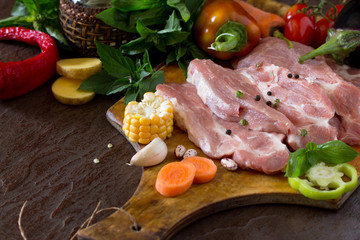 Fresh raw meat pork fillet with vegetables on the cutting board.