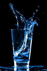 Ice cubes splashing into glass of wate