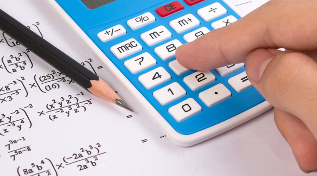 Hand press calculator on mathematical or math equations. Math homework or math exams. Solving mathematical problem. Math formula concepts.