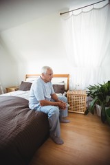 Thoughtful senior man sitting on bed