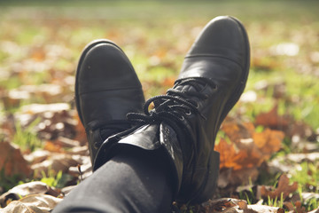 Female legs in boots on the autumn leaves. Feet shoes walking in