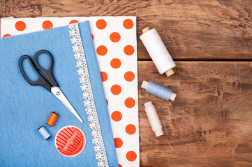 Handmade and sewing background. Fabric for sewing, lace and accessories for needlework on old wooden background. Spool of thread, scissors, buttons, sewing supplies. Set for needlework top view