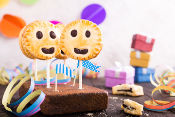Homemade shortbread smiley cookies with dark chocolate on stick called pie pops. Children's party background.