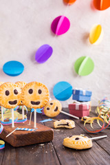 Homemade shortbread smiley cookies with dark chocolate on stick called pie pops. Children's party background.