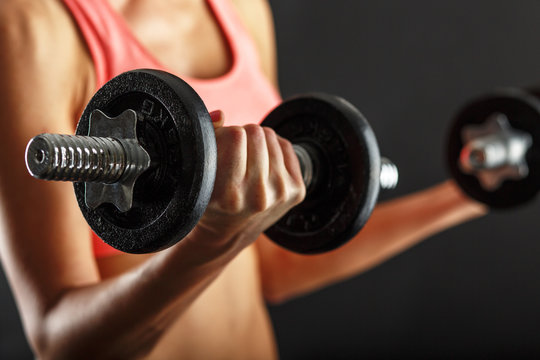 Fitness female woman with muscular body, doing her workout with dumbbells