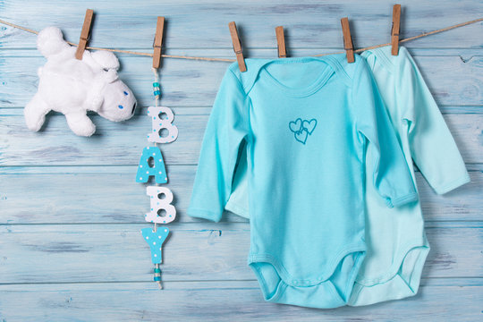 Baby clothes, white toy bear and word baby on a clothesline