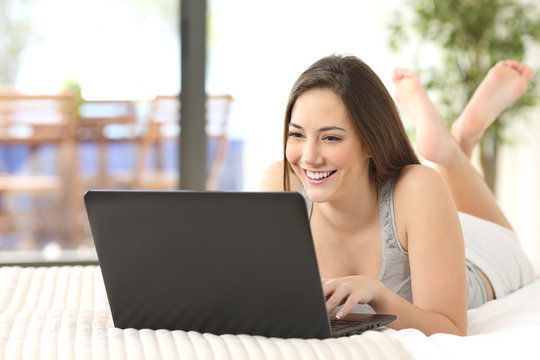 Happy teen browsing laptop online at home