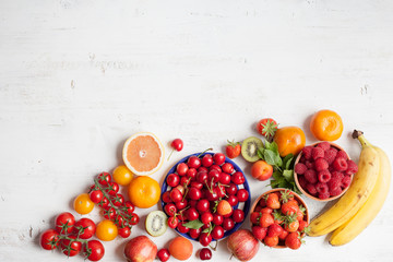 Summer fruits and berries (strawberries, cherries, raspberries, oranges, grapes, persimmon) on a white table, space for text, selective focus