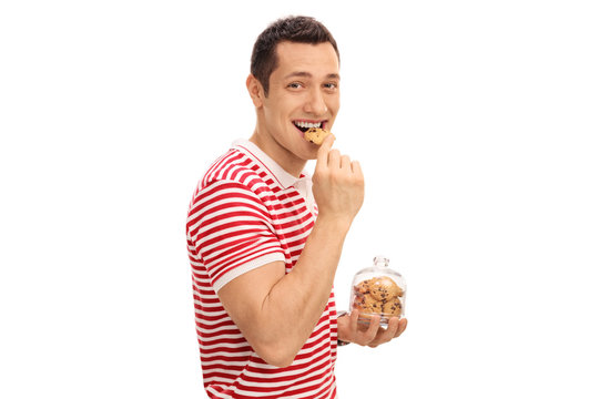 Young guy eating cookie and holding cookie jar
