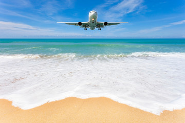 Fototapeta na wymiar Airplane landing above beautiful beach and sea background.