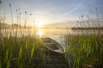Fototapeta łódka zacumowana do drewnianego pomostu nad  jeziorem obraz