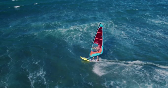 Aerial view of windsurfer gliding across blue ocean, extreme sport