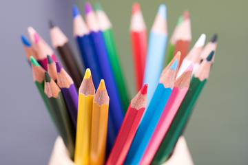 Fototapeta premium Color pencils on the table in the container with background lights. Colorful pencils in a variety of colors. Back to school concept. Closeup. Selective focus.