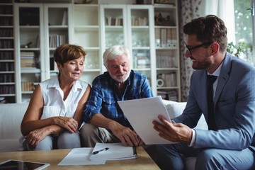 Senior couple planning their investments with financial advisor - obrazy, fototapety, plakaty
