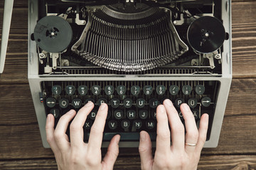 Writer typing with retro writing machine. View from above.