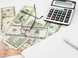 White office desk table with pen calculator glasses and banknote