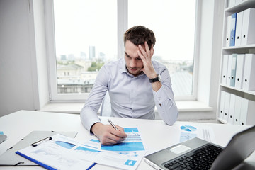 stressed businessman with papers in office
