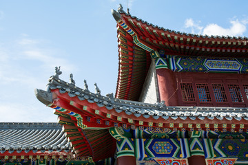 Fototapeta premium Part of eastern pagoda in sky background. Picturesque wooden elements of colorful roof.