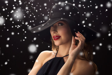 beautiful woman in black hat over snow