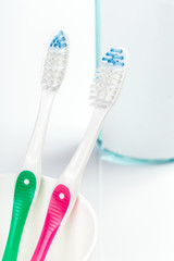 Toothbrushes in glass on table on light background