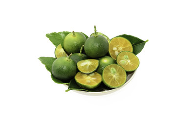 Cut limes and green leaves in a small bowl on white background.