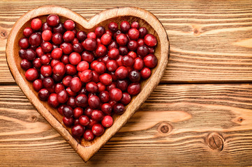 Cranberries on wooden tray on brown  wooden background.