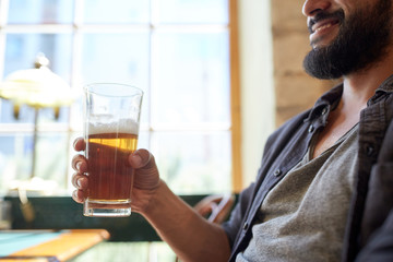 close up of happy man drinking beer at bar or pub