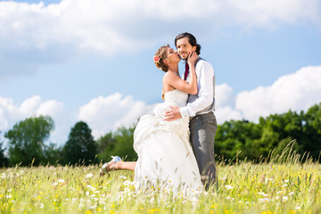 Hochzeitspaar küsst auf einem Feld
