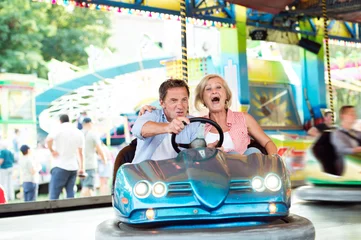 Deurstickers Senior couple in the bumper car at the fun fair © Halfpoint