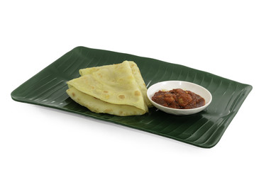 Two slices of homemade plain pancake with shrimp gravy or sambal udang on green banana leaf plate on white background