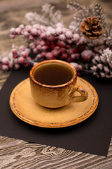 Small cup of coffee, fir branch in snow on wooden background