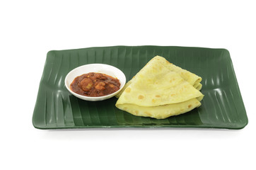 Two slices of homemade plain pancake with shrimp gravy or sambal udang on green banana leaf plate on white background