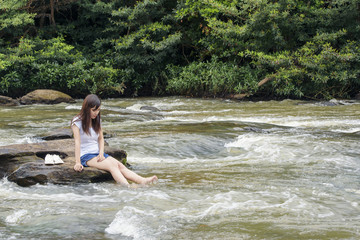 Asian sexy woman sitting on the stone splatter in cascade, Thail