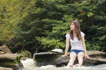 Asian sexy woman sitting on the stone splatter in cascade, Thail