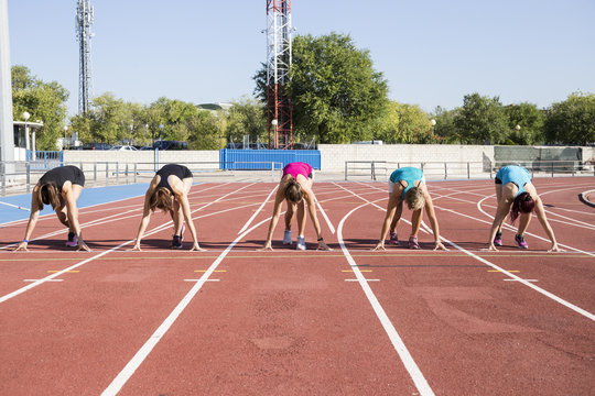 Female runners on tartan track in starting position