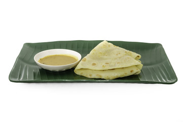 Two slices of homemade plain pancake with curry on green banana leaf plate on white background
