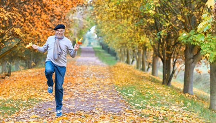 Fototapeta premium glücklich springender Senior im Herbst im Park, Lebensfreude