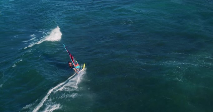 Aerial view of windsurfer gliding across blue ocean, extreme sport