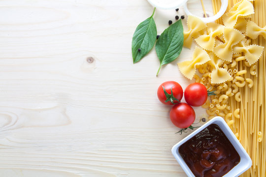 spaghetti with ingredients for cooking on wood background