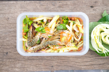 Spicy mango salad with horse crab in box on wood table