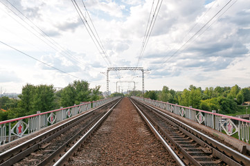 Obraz premium Straight railroad on bridge vanishing in horizon with power line against skyline background. Moscow, Russia. 