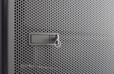 Door perforated  of server rack cabinet. The key is inserted into the door lock. Side lighting and  shallow DOF