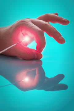 Bright light source on the end of the probe between big and index fingers  the left hand  the person