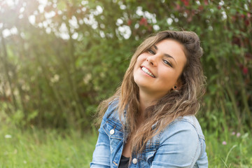 Naklejka premium Smiling teenage girl outdoors in sun light. Girl is looking at the camera. 