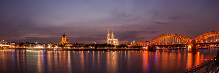 Obraz premium Illuminated Cologne Cathedral and bridge at night in Cologne, panoramic view