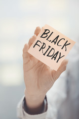 Woman holding adhesive note Black Friday text