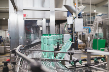 Industrial factory indoors and machinery. Robotic factory line for processing and bottling of pure spring water into canisters and bottles. Selective focus. Short depth of field.