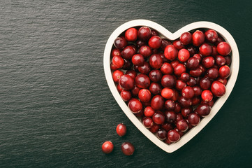 Cranberries on white tray on black background.